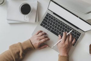 working man is typing on black frame laptop